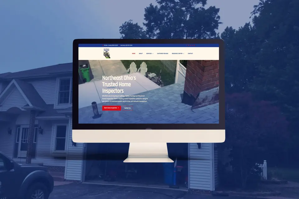 Home inspector website on a desktop monitor in front of a two story house